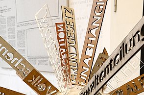 Foto einer Skulptur eines Kopfes, in welchem Pfeile mit Sätzen abstehen