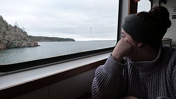 Person schaut aus dem Fenster eines Schiffs 
