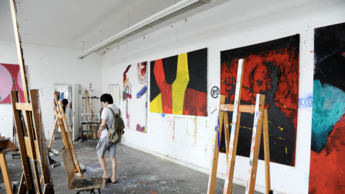 Atelier mit aufgehängten Gemälden und Staffeleien 