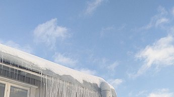 Foto eines Gebäudes auf dem Schnee liegt und Eiszapfen vom Dach hängen