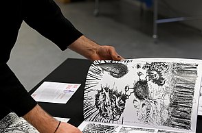 Foto einer Person die durch Skizzenbücher schaut