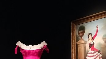 Foto eines pinken Kleides mit weißen Rüschen neben dem ein eingerahmtes Bild hängt