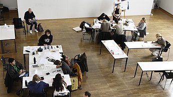 Studenten sitzen an verschiedenen Tischen