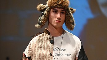 Ein Model trägt ein bunt-zusammengenähtes Outfit mit einer Ushanka
