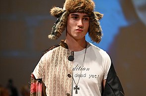 Ein Model trägt ein bunt-zusammengenähtes Outfit mit einer Ushanka