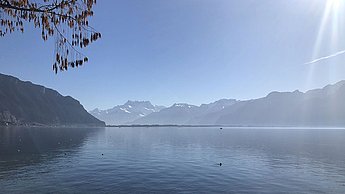 Foto eines Sees hinter dem eine Berglandschaft steht