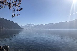Foto eines Sees hinter dem eine Berglandschaft steht