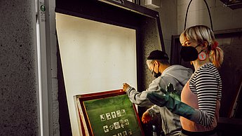Personen stehen vor einer Leinwand