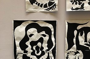 Foto einer Sammlung aufgehängter Bilder die nur mit schwarzer Farbe gemalt sind