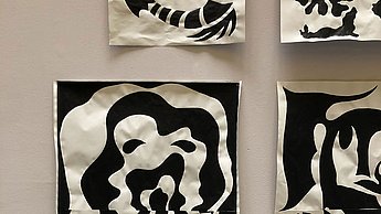 Foto einer Sammlung aufgehängter Bilder die nur mit schwarzer Farbe gemalt sind