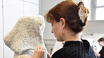 Person arbeitet an Kleidung von einer Modepuppe