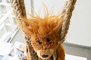 Foto einer Plüschfigur eines Löwen, die an zwei Seilen herabhängt