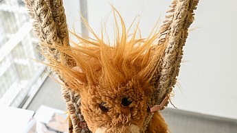 Foto einer Plüschfigur eines Löwen, die an zwei Seilen herabhängt
