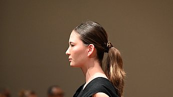 Foto eines Models mit einem schwarzen Kleid und einer Tasche aus Leder