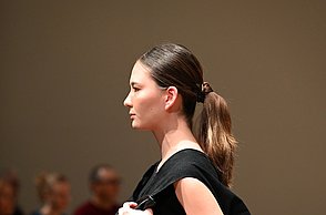 Foto eines Models mit einem schwarzen Kleid und einer Tasche aus Leder