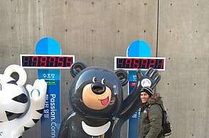 Person gibt dem Olympia Maskottchen ein High Five